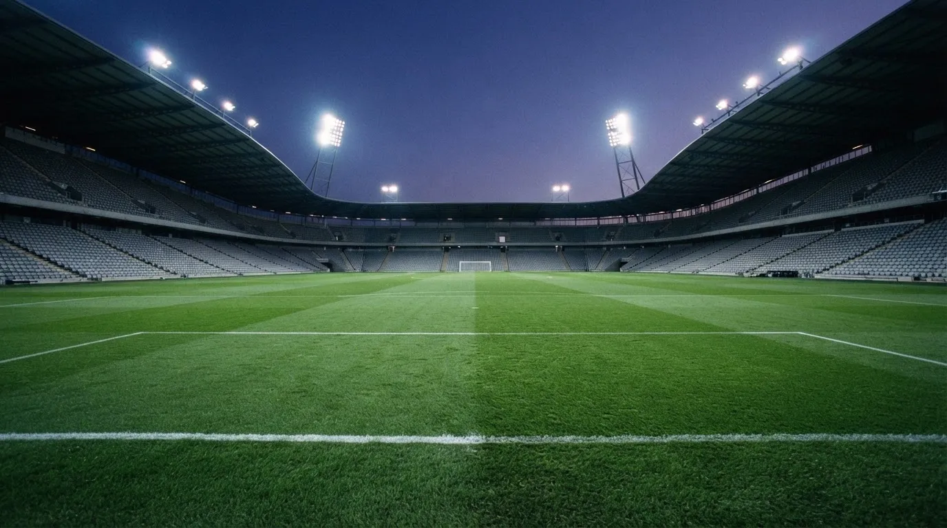 An empty football stadium with floodlight masts at dusk