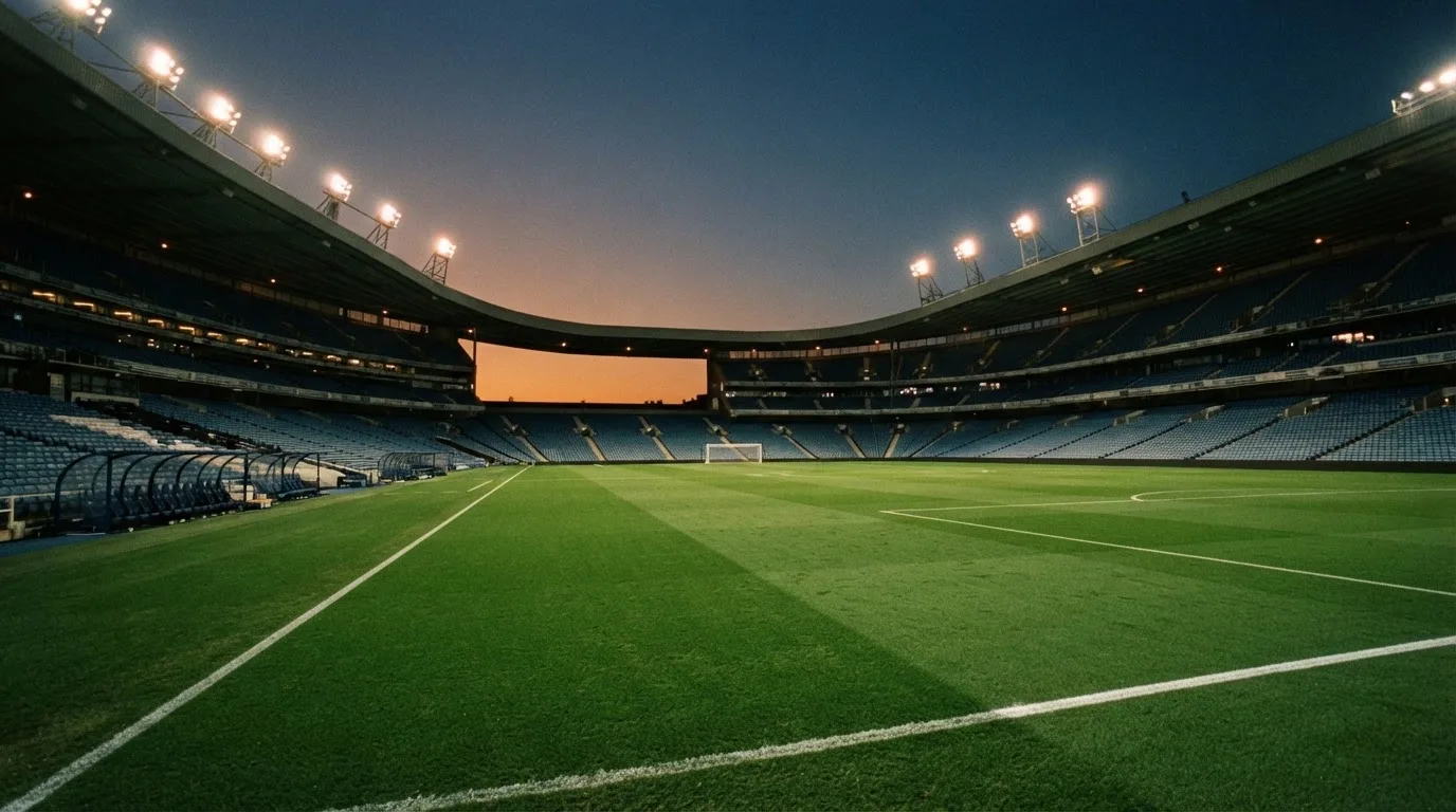 An empty football stadium with floodlight masts at dusk