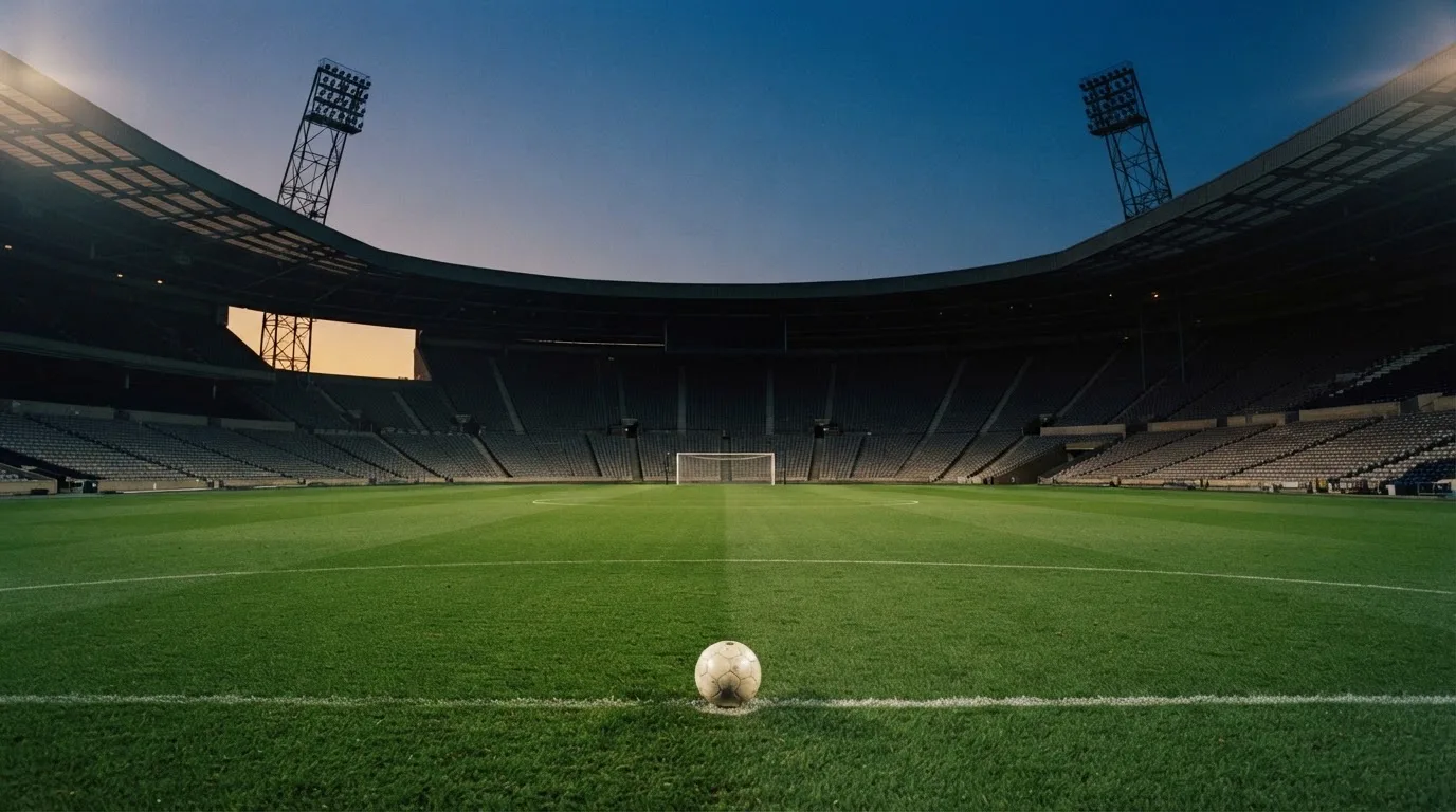 An empty football stadium with floodlight masts at dusk