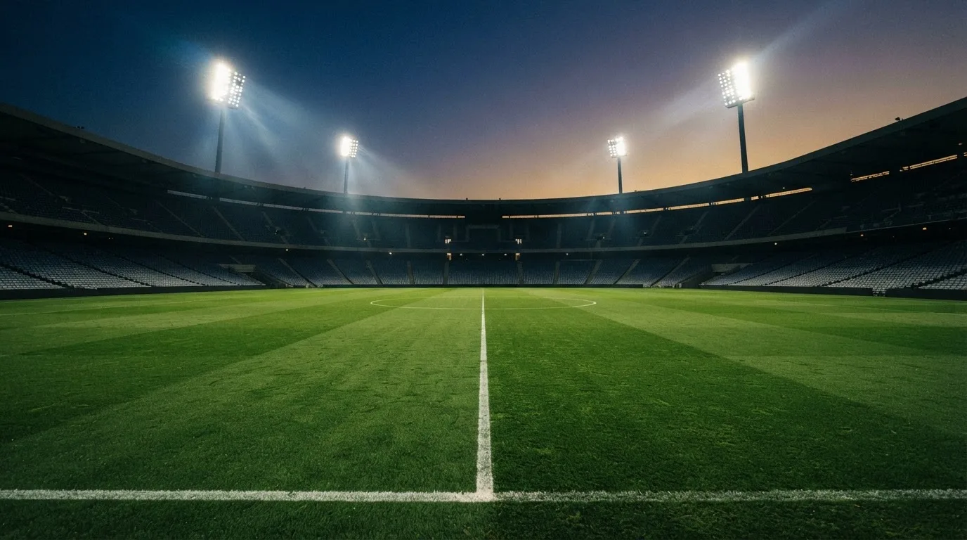 An empty football stadium with floodlight masts at dusk