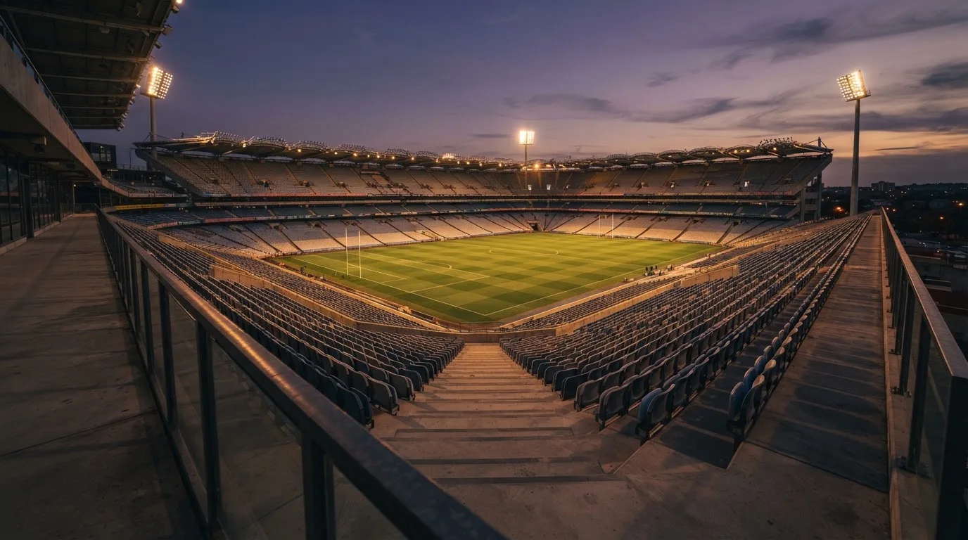 An empty football stadium with floodlight masts at dusk