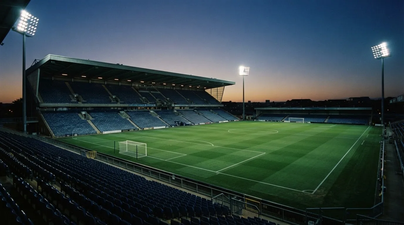 An empty football stadium with floodlight masts at dusk