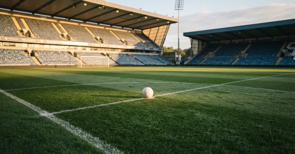 A ball on the centre spot of a grass pitch in morning light